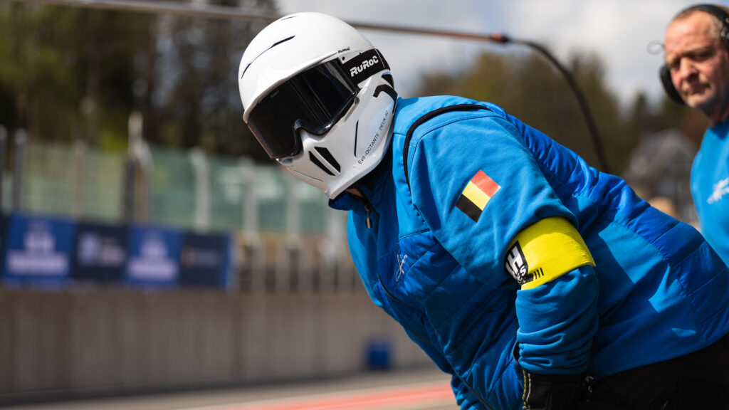 Pitcrew member with a white helmet waiting for his racecars to arrive for a Pit stop